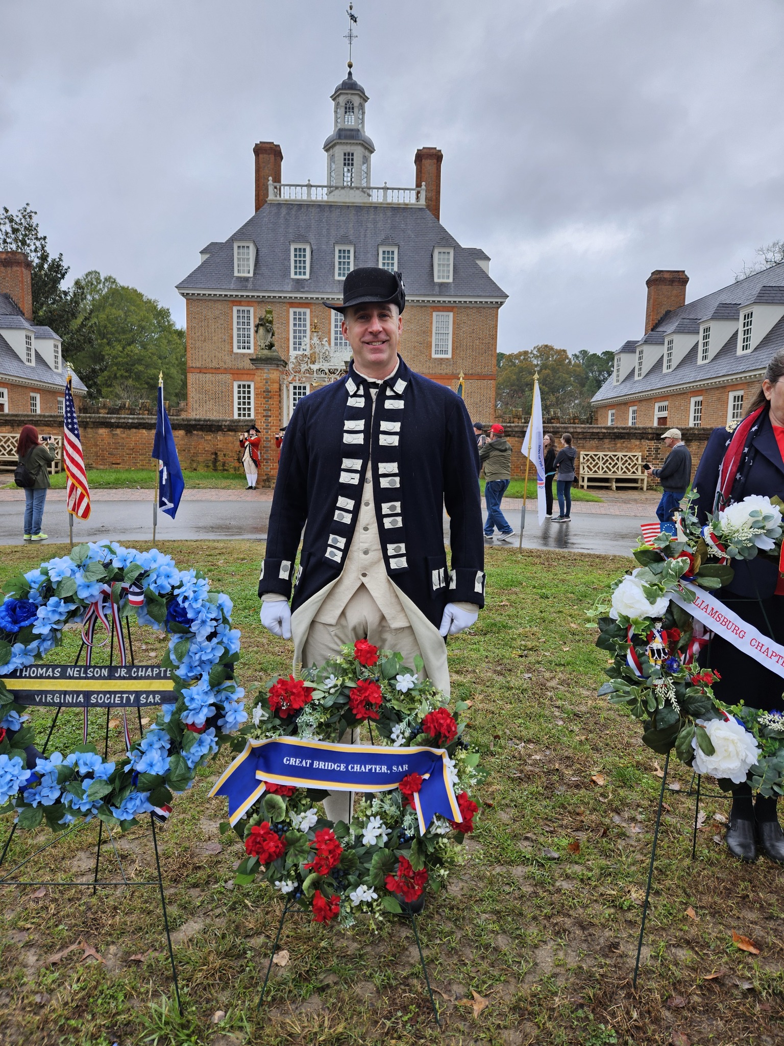 Great Bridge chapter compatriot in colonial attire standing with chapter wreath in honor of Veteran's Day at Colonial Williamsburg.